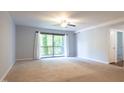 A spacious living room with neutral carpet, fan, and a sliding glass door to the balcony at 514 Pine Ridge Pl, Raleigh, NC 27609