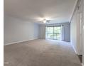 A spacious living room with neutral carpet, ceiling fan, and a sliding glass door at 514 Pine Ridge Pl, Raleigh, NC 27609