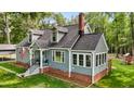 View of the home's exterior showcasing dormer windows, an enclosed sunroom, brick foundation, and a welcoming entrance at 1052 Hughes Trl, Elon, NC 27244