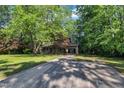 View of the house from the long driveway, surrounded by mature shade trees and well kept lawn at 1115 Chestnut Dr, Smithfield, NC 27577