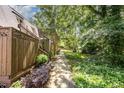 A cozy walkway extending through a backyard that is canopied by shade trees, and adorned with lush greenery at 119 Brookberry Cir, Chapel Hill, NC 27517
