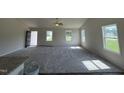 Bright open floor plan with large windows, carpet in the living room, and wood floors in the kitchen at 128 Coharie Dr, Lillington, NC 27546