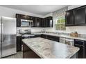 A modern kitchen with stainless steel appliances, dark cabinets, and granite countertops, perfect for cooking at 1537 Ivy Meadow Ln, Zebulon, NC 27597