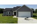 Charming single-story home featuring gray siding and a two-car garage on a green lot at 166 Coharie Dr, Lillington, NC 27546