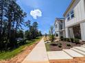 New home featuring modern design, manicured landscaping, and scenic sidewalk access near wooded area and lake at 330 Cottage Hill Way, Knightdale, NC 27604