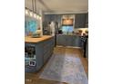 Modern kitchen featuring gray cabinets, stainless steel appliances, an island and a stylish rug at 3620 Arrowwood Dr, Raleigh, NC 27604