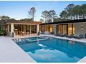 Stunning backyard pool with a lounge area surrounded by large glass windows and greenery at 812 Stradella Rd, Raleigh, NC 27614