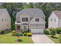 Two-story home featuring a well-manicured lawn, mature trees, and a two-car garage at 1008 Justice Walk Ave, Morrisville, NC 27560