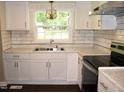 Bright kitchen features white cabinets, subway tile backsplash, and stainless steel appliances at 10180 Buffalo Rd, Clayton, NC 27527