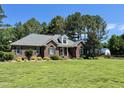 Charming brick home, well-manicured lawn, mature trees, and architectural details on a clear, sunny day at 108 Cedarwood Dr, Louisburg, NC 27549