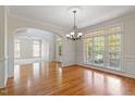 Elegant dining room with hardwood floors, chandelier, and large windows creating a bright and inviting atmosphere at 117 Arborhill Ln, Holly Springs, NC 27540