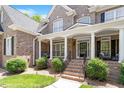 Inviting front porch features brick stairs, white columns, iron railings, and tasteful landscaping around the property at 117 Arborhill Ln, Holly Springs, NC 27540