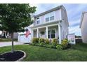 Inviting two-story home featuring a covered porch, lush landscaping, and an American flag at 1254 Salters St, Burlington, NC 27215