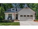 Inviting front exterior featuring a charming porch, stone accents, and a classic two-car garage at 136 Hatchet Cv, Louisburg, NC 27549