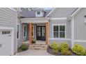 Inviting front entrance with wood columns, a dark front door, and manicured shrubs at 14 Duck Bill Trl, Pittsboro, NC 27312
