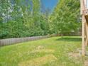 Large, grassy backyard with a wooden fence and mature trees providing privacy and shade at 2317 Colony Woods Dr, Apex, NC 27523