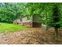 View of the back of the home showing the back entrance and access to utilities and surrounded by mature trees at 2832 Ladale Ln, Mebane, NC 27302