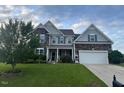 Charming two-story home with stone and siding, lush lawn, and a two-car garage at 30 Sunbury Ct, Zebulon, NC 27597