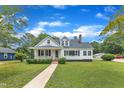 Charming white bungalow featuring a brick chimney and a well-manicured front lawn at 302 Hester St, Knightdale, NC 27545