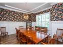 Formal dining room with hardwood floors, detailed wallpaper, chair rail trim, and a decorative light fixture at 3128 Mountain Hill Dr, Wake Forest, NC 27587