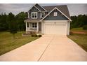 Inviting home exterior featuring a two-car garage, covered porch, and a lush green lawn at 474 Ashpole Trl, Clayton, NC 27520