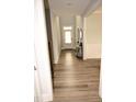 Hallway with hardwood flooring, neutral walls, and trimwork, leading to the front door at 474 Ashpole Trl, Clayton, NC 27520
