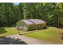 Inviting single-story home with a metal roof, gravel driveway, and surrounded by lush greenery at 560 Parker Creek Rd, Holly Springs, NC 27540