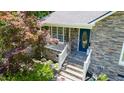 Charming home entrance featuring stone accents, a blue front door, and meticulously landscaped surroundings at 856 Williams White Rd, Zebulon, NC 27597