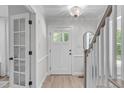 Bright foyer featuring light wood floors, a white front door with glass panes, and modern lighting fixture at 11817 Coachmans Way, Raleigh, NC 27614