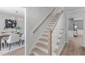 Staircase with light wood treads, white risers and railing, with view into a dining room with chandelier at 11817 Coachmans Way, Raleigh, NC 27614