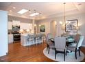 Open dining area with modern lighting, wood floors, and kitchen view at 1205 Bridgeforth Ln, Chapel Hill, NC 27517