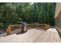 Outdoor living on a spacious wooden deck with a stainless steel grill and wooded views at 130 S Creek Dr, Louisburg, NC 27549