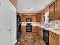 Well-equipped kitchen featuring wood cabinetry, black appliances, and tile flooring, offering a functional cooking space at 1325 Red Brick Rd, Garner, NC 27529