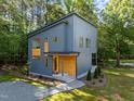 Contemporary home exterior featuring unique architectural design, nestled amongst mature trees and manicured landscaping at 160 Daphine Dr, Hillsborough, NC 27278