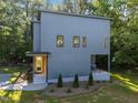 A modern home with gray siding and black trim, surrounded by greenery and manicured landscaping at 160 Daphine Dr, Hillsborough, NC 27278