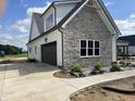 A garage is attached to a stylish new construction home featuring stone and white siding at 188 Banner Elk Rd, Benson, NC 27504