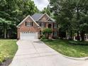 Beautiful brick home with a spacious driveway, lush green lawn, and mature trees offering shade and curb appeal at 203 Chilcott Ln, Apex, NC 27502