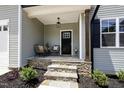 Inviting covered front porch featuring stone steps, modern chairs and planters, perfect for relaxing at 220 Purslane Dr, Franklinton, NC 27525