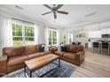 Living room with hardwood floors, large windows, leather sofa, and a ceiling fan at 220 Purslane Dr, Franklinton, NC 27525