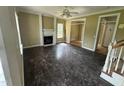 Empty living room featuring a decorative fireplace, hardwood floors and natural lighting, needing renovation at 2377 Vinson Rd, Clayton, NC 27527