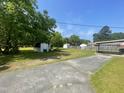 Expansive backyard showcasing a large grassy area, mature trees, and storage sheds; perfect for outdoor activities at 3301 Amherst Rd, Rocky Mount, NC 27804