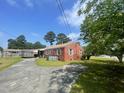 Rear exterior view of a brick home with a concrete patio and driveway, surrounded by a well-kept lawn at 3301 Amherst Rd, Rocky Mount, NC 27804
