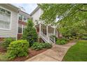 Charming two-story home with a covered front porch, red front door, landscaped yard, and brick and siding exterior at 3923 Napa Valley Dr, Raleigh, NC 27612