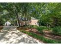 Traditional brick home on a wooded lot with a long driveway and lush landscaping at 4020 Gumleaf Dr, Apex, NC 27539