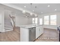 Open concept kitchen island with marble countertops, stainless steel appliances, and an adjacent staircase at 408 Longleaf Glen Lane, Zebulon, NC 27597