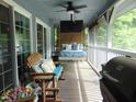 Relaxing screened-in porch with outdoor seating, a bed swing, ceiling fan, and a mounted TV at 4144 Fairport Rd, Kittrell, NC 27544
