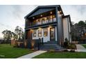 Two-story home with a balcony, elegant lighting, and stone steps leading to the front entrance at 500 Grigsby Ave, Holly Springs, NC 27540