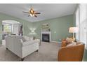 Cozy living room with a fireplace, neutral furniture, ceiling fan, and an archway to the kitchen at 576 Prairie Ln, Lillington, NC 27546