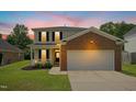 Beautiful two-story home at dusk with brick accents, large windows, manicured lawn, and an attached garage at 634 Cotton Brook Dr, Fuquay Varina, NC 27526