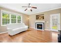 Bright living room with a fireplace, ceiling fan, large windows, hardwood floors, and neutral paint at 634 Cotton Brook Dr, Fuquay Varina, NC 27526